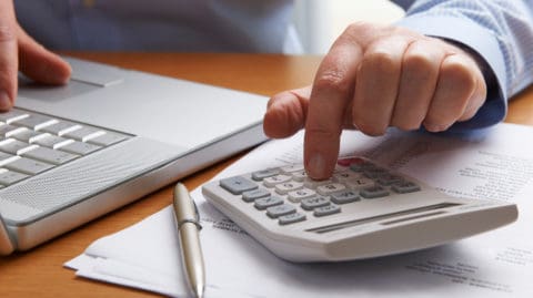 Person Calculating Personal Injury Compensation on a Calculator